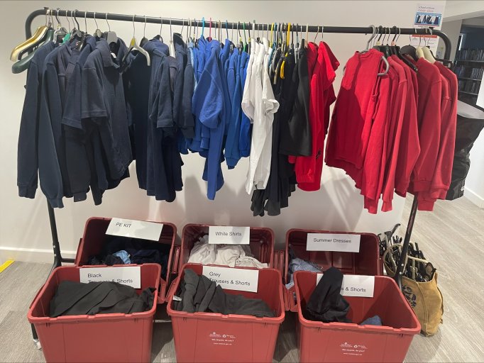 An image of school uniform arranged on a hanging rail and in red boxes.